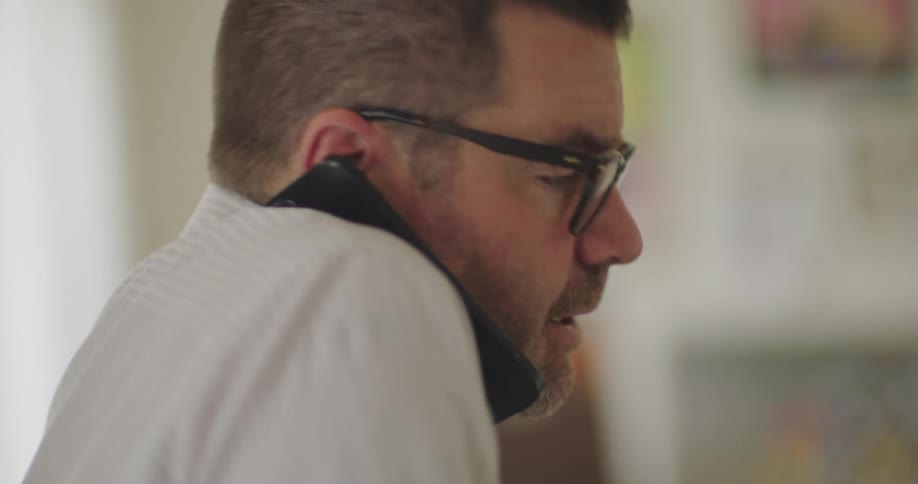 Man typing on a laptop and talking on the phone at the same time