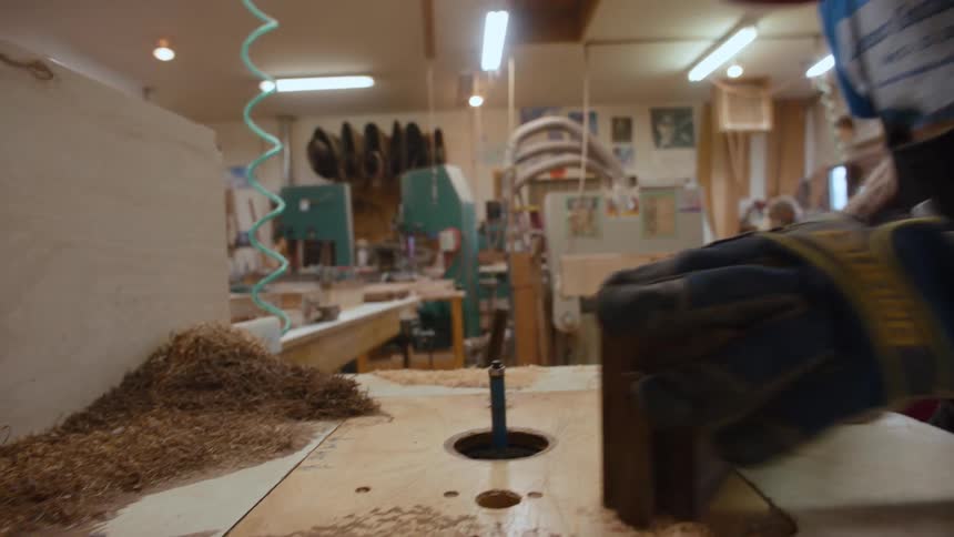 Carpenter in an indoor environment scraping a piece of wood
