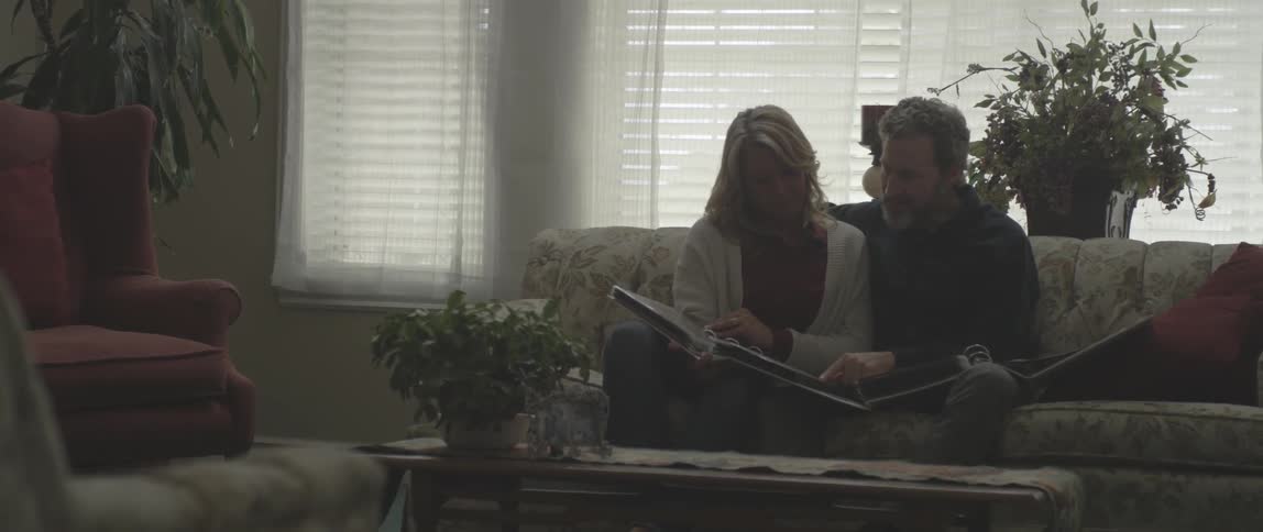 A man and woman look at photo albums on a couch