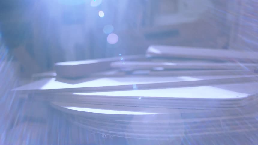 A stack of variously shaped wooden pieces lies flat on a surface with a blurred background suggesting a workshop setting