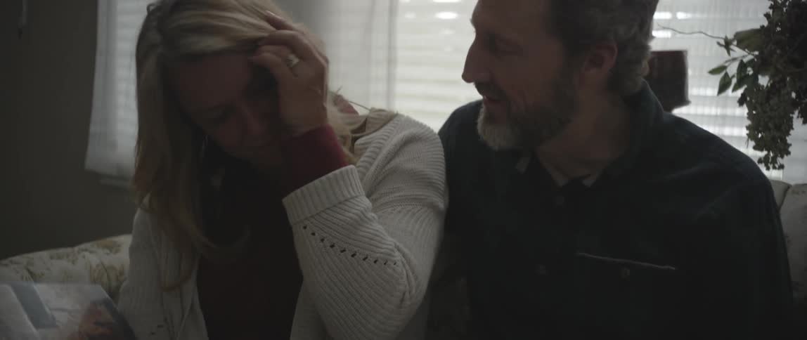 A man and woman look at photo albums while sitting on a couch