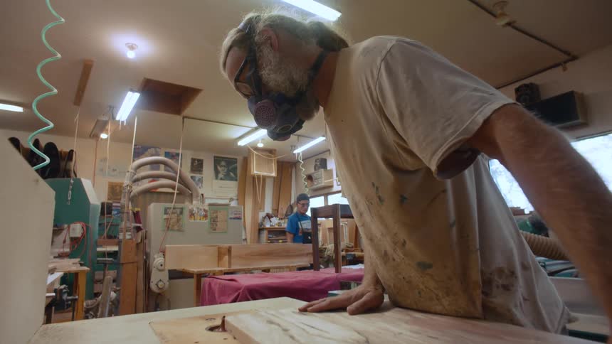 Carpenter with protective mask working on a wooden sheet