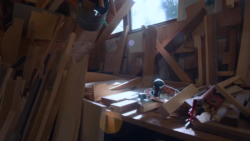 Cluttered woodworking bench with scraps of wood tools and a measuring ruler illuminated by natural light from the window