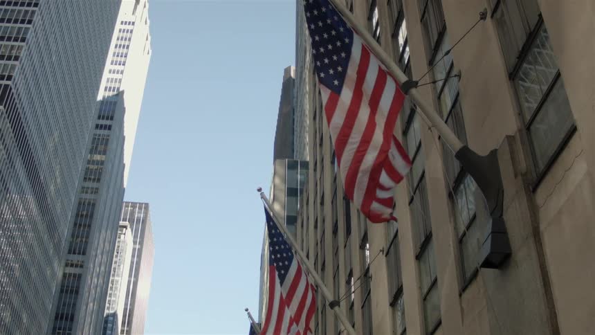 Flags blow in the wind on the side of a building