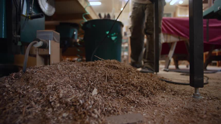 A pile of sawdust is in the corner of the shop