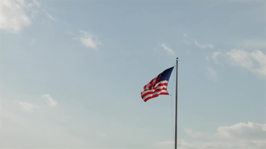 A flag flies in the breeze on a mostly clear day