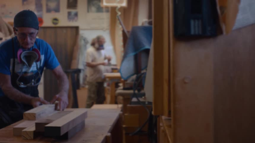 Two male carpenters with protective gear working in a workshop