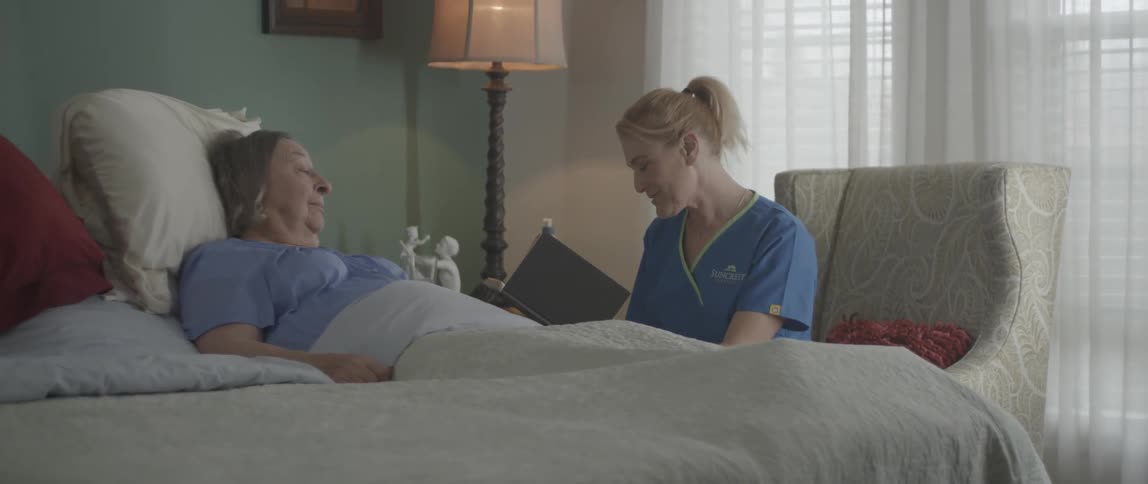A nurse reads from a book to a woman laying down