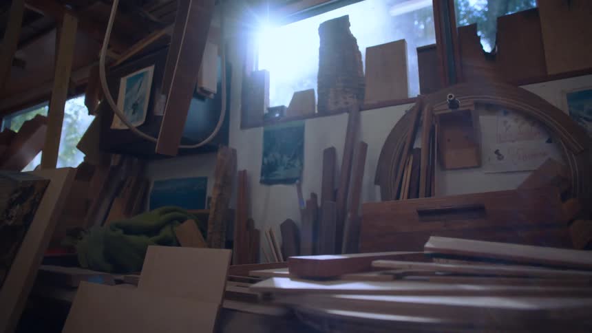 Tools and wooden pieces inside a workshop with sunlight reflecting