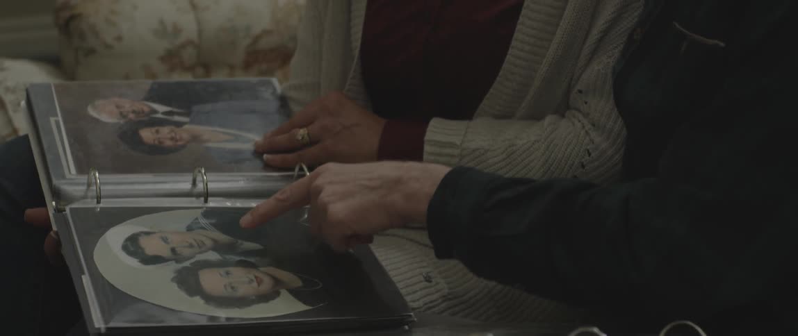 A man and woman sit and browse through photo albums