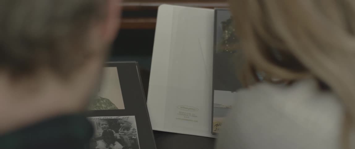 A man and woman sit and browse through photo albums