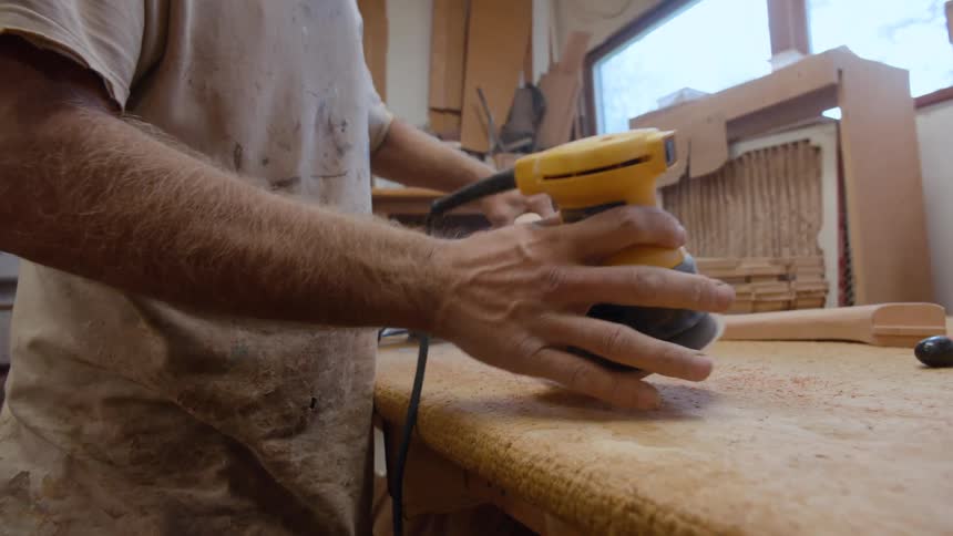 Carpenter with a machine shaping a piece of wood
