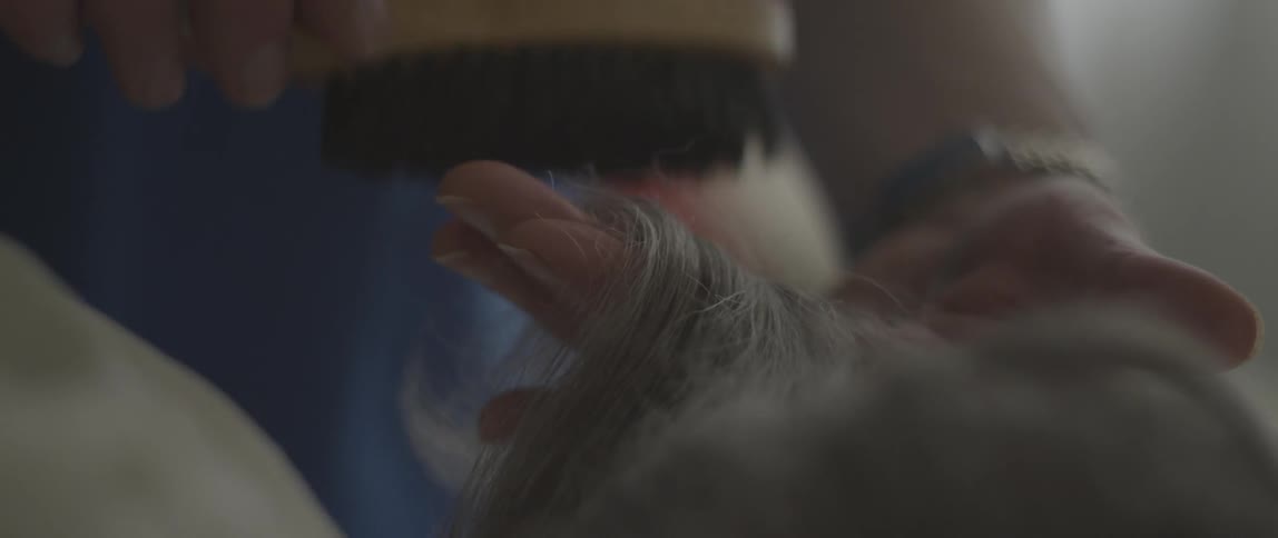 A woman brushes someone's hair