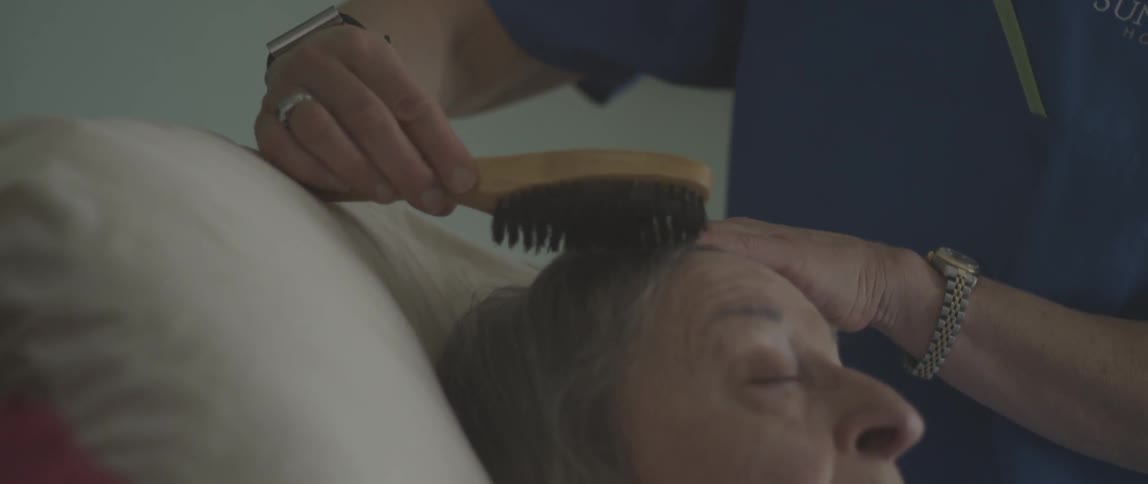 Nurse brushes and elderly patient's hair