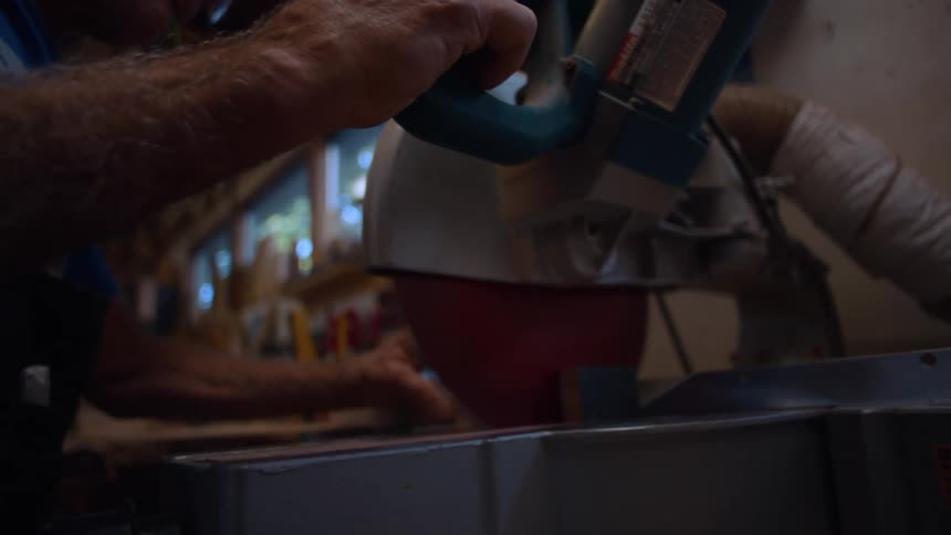 Carpenter with an electric circular saw cutting pieces of wood