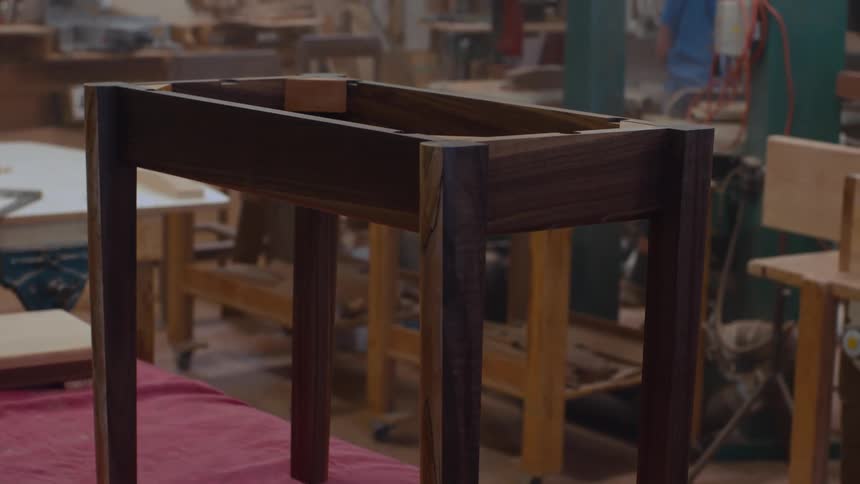 A wooden frame structure stands in the center of a cluttered workshop