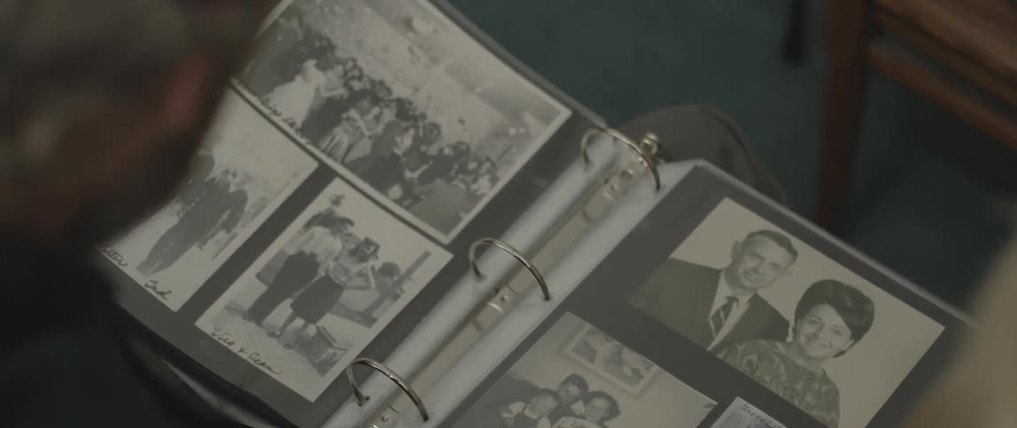 A man and woman sit and browse through photo albums