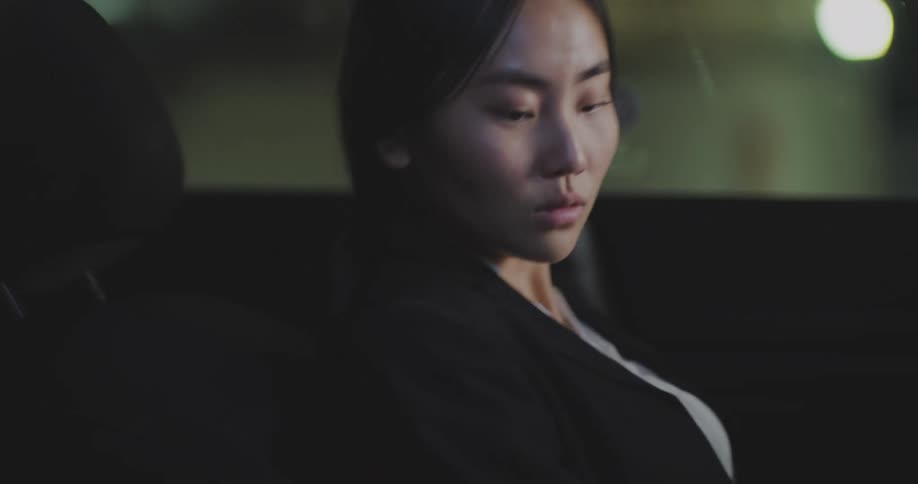 A young woman sleeping in a car wakes up startled by the sound of a smartphone