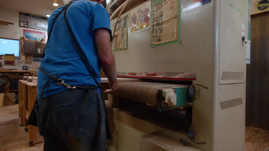 Carpenter picking up a sheet of wood in a machine
