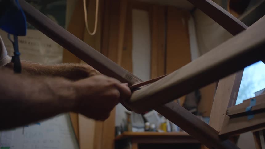 A man is carving a wooden chair