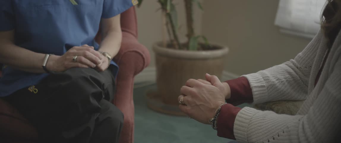 A nurse touches the arm of a patient at home