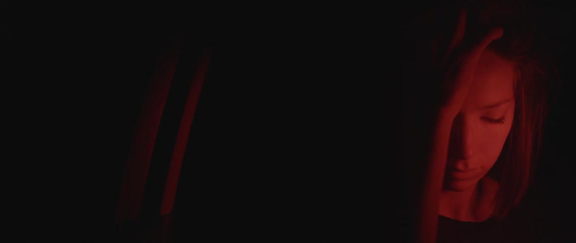A woman brushes her hair in the dark with her hands