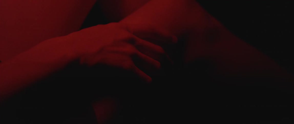 A hand rests on a thigh and is lit by a red light