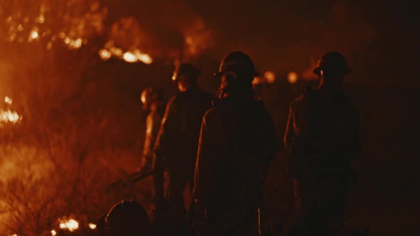 Firefighters dealing with a wildfire at night