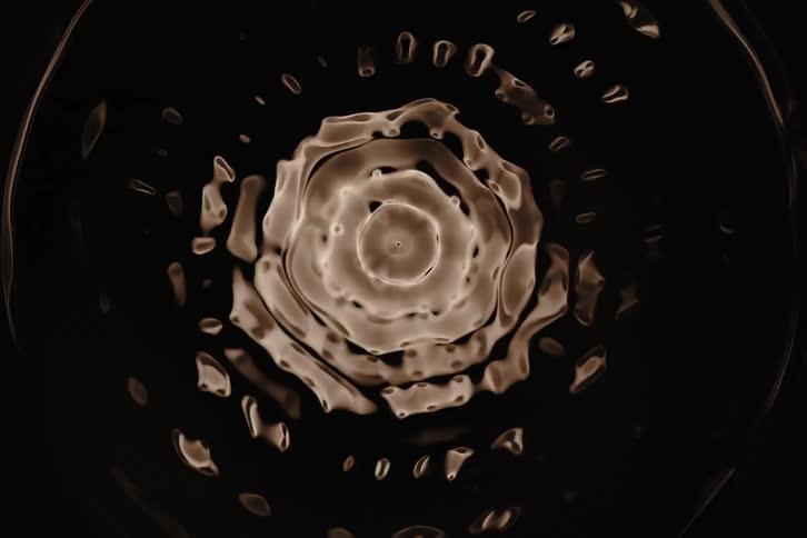 An abstract pattern of concentric circles and radiating lines glows with a warm textured light against a dark background