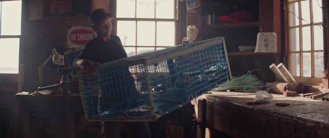 Person moving a blue fishing trap in a workshop