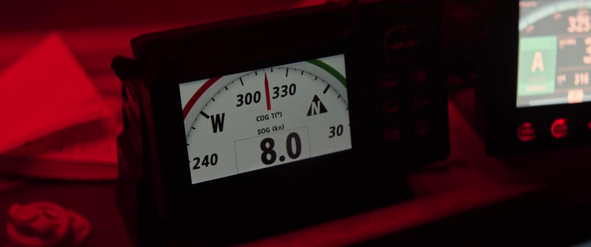 Screen of a marine navigation instrument at night showing speed and direction