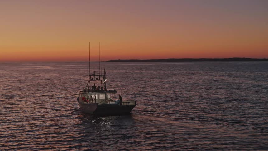 Fishing boat traveling across the ocean as the sun rises