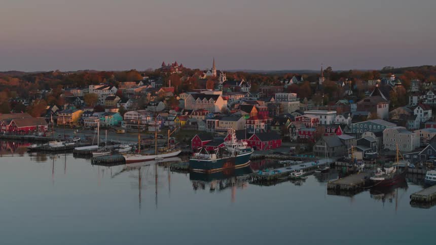 Aerial view of a coastal town with colorful houses and boats moored in the harbor at dusk