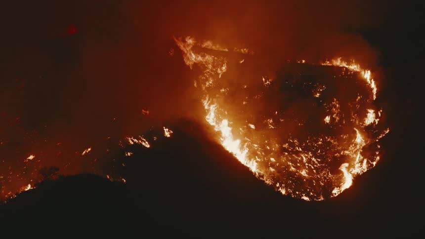 A forest fire on a hill at night and with very orange fire