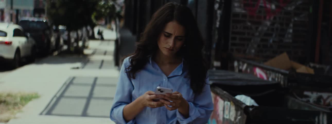 Woman throwing trash and taking an iphone out of her pocket
