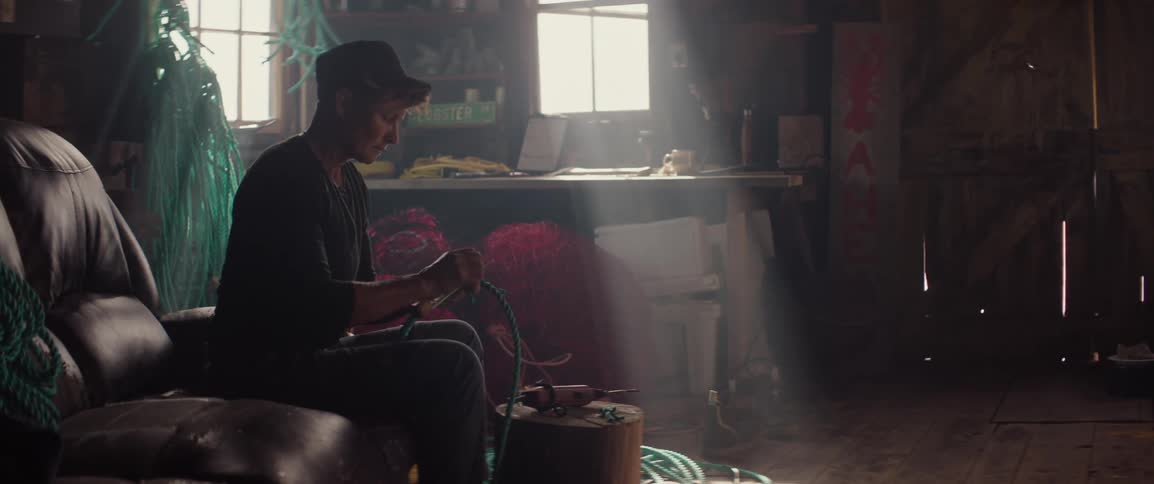 A woman is cutting rope with a knife in a fisherman's workshop