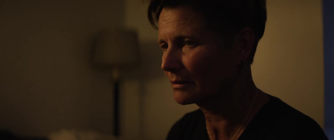 Woman sits in her house as beams of light move across her face