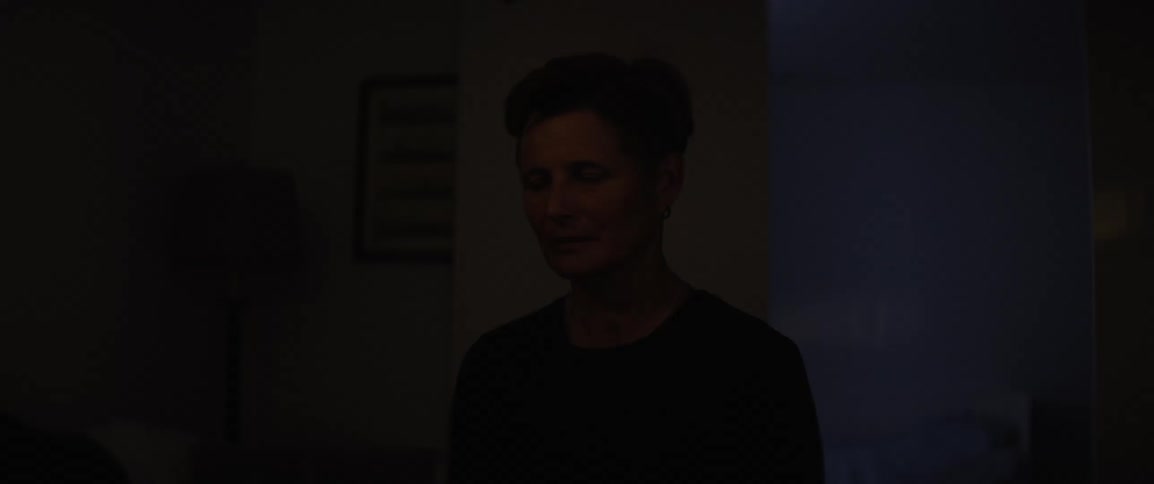 Person sitting in a dark room with a beam of light passing through