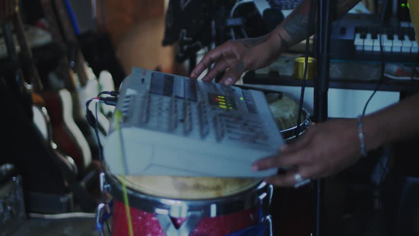 Person operating a portable mixing board resting on a drum