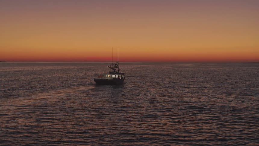 Isolated fishing boat traveling out to sea at dawn