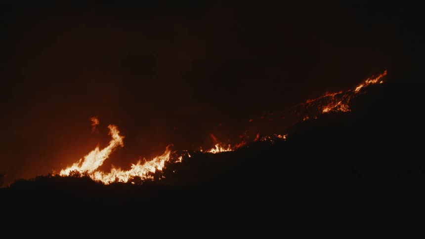 Forest fire spreads across a hillside overnight