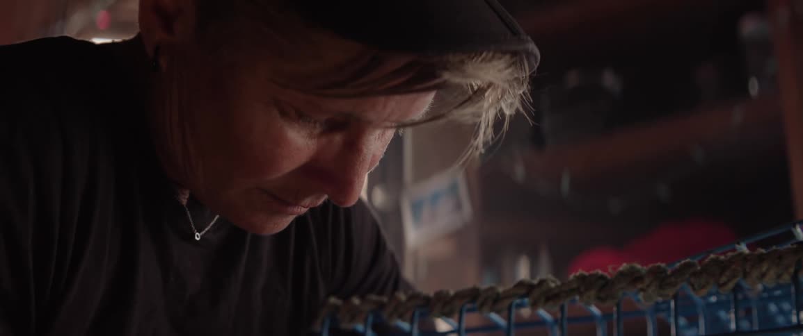 Portrait of a woman in a cap concentrating while fixing a lobster trap