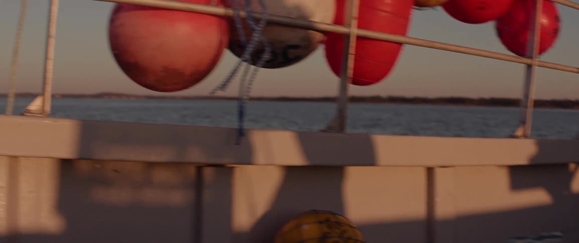 Shadow of a person carrying a fishing trap on a boat at sunrise