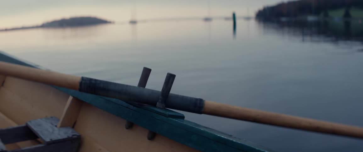 Oars from a rowboat seen pushing through the water at sunrise