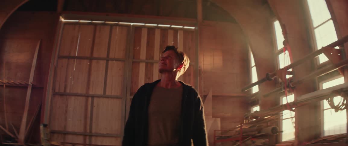 Person walking inside a large rustic wooden boat shed