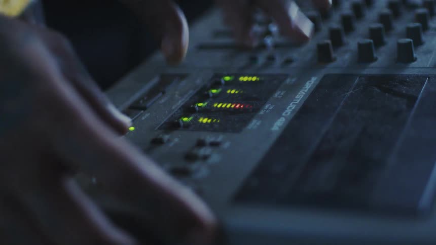 Pair of hands interacting with a music mixer