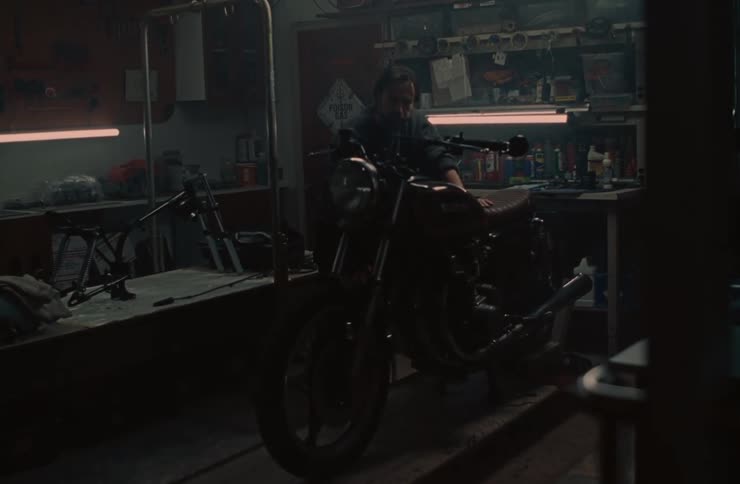 Man starting a motorcycle inside a workshop