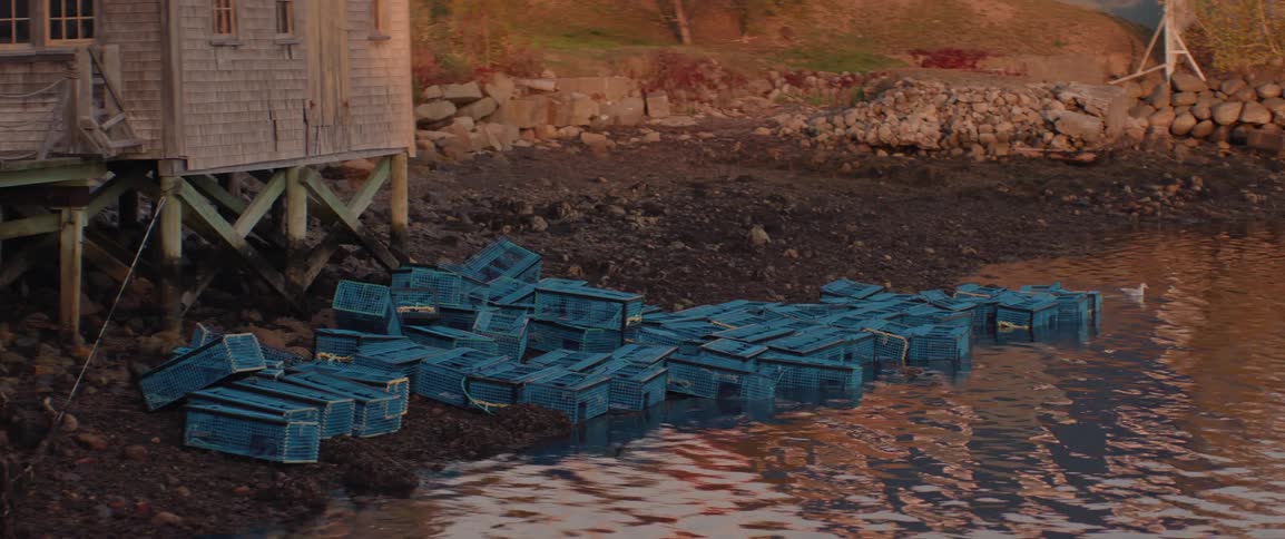 Lobster traps stored along the shore near a wharf