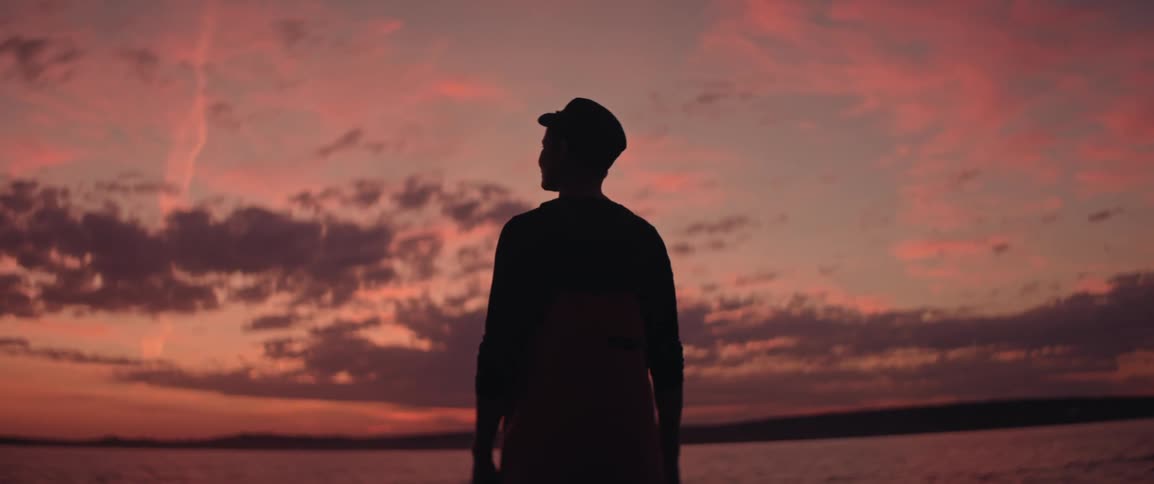 Female silhouette standing seaside watching the sunset