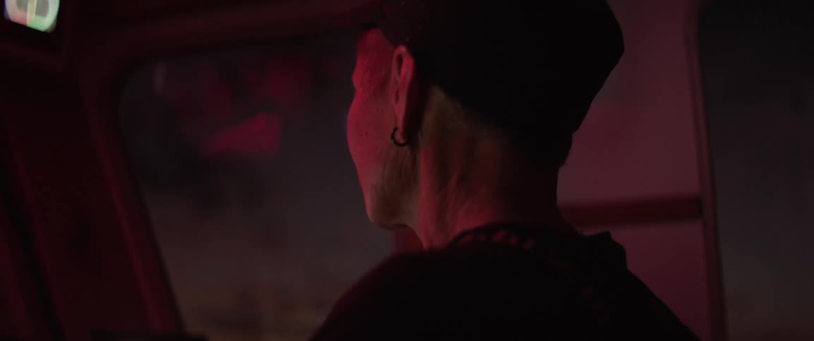 Closeup of a woman driving a boat at night under red lights in the cabin